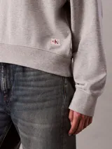 Buzo Calvin Klein de tejido terry color gris melange, con cuello en V, manga larga y costura vertical central en el frente.