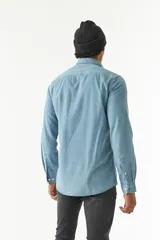 Camisa de jean azul de manga larga con dos bolsillos frontales con solapa abotonada.