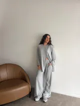 Conjunto de dos piezas color gris melange, confeccionado en tela de lanilla, compuesto por un buzo de manga larga con diseño cruzado al frente y un pantalón largo de corte holgado y tiro alto.