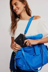 Billetera de cuero color negro con acabado gastado, diseño alargado, cierre perimetral de cremallera y tirador de cuero trenzado. Cuenta con bolsillo exterior con cierre y marca grabada en el frente.