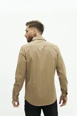 Camisa de manga larga lisa con cuello clásico y cierre frontal de botones. Presenta un ajuste regular y un pequeño logo bordado en el pecho.