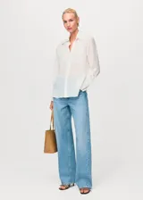 Camisa de corte recto y diseño clásico, confeccionada en tejido mezcla de lyocell y poliamida. Presenta cuello camisero, cierre frontal de botones ocultos, mangas largas con puños abotonados y detalles de parches decorativos en el frente.