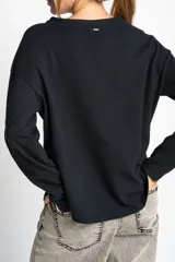Sweater de algodón negro con calce oversize, cuello redondo y mangas largas con detalle de línea blanca lateral.
