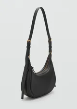 Riñonera de diseño minimalista en color negro, confeccionada en material efecto piel con acabado liso. Presenta una forma curva estructurada, cierre superior con cremallera y una correa ajustable con hebilla metálica que permite llevarla al hombro o cruzada.
