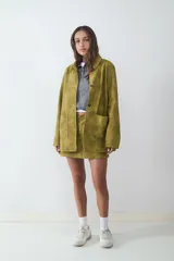 Pollera mini color verde oliva con efecto desgastado, dos bolsillos delanteros y cierre oculto. Confeccionada en tejido plano.