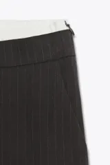 Pantalón de tiro alto color gris oscuro con finas rayas verticales blancas (pinstripe). Posee pernera recta y ancha, y doble cintura elástica con tejido combinado.