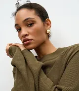 Vestido midi de punto color verde oliva, con cuello redondo y mangas largas. Presenta una textura acanalada y un diseño ajustado que realza la silueta.