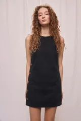 Vestido corto negro de silueta recta y calce relajado, con escote redondo, diseño sin mangas y detalle de botones laterales.