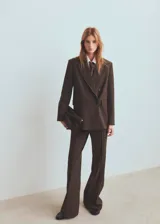 Blazer de corte sastre con diseño de doble botonadura, confeccionado en tejido con patrón de cuadros sutiles. Presenta solapas clásicas, bolsillos con solapa y una estructura entallada que aporta un estilo formal y sofisticado.