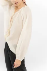 Blusa celeste de algodón con escote en V con lazos y mangas largas abullonadas con puños elásticos.