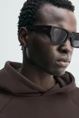 Sudadera de corte boxy fit en color marrón oscuro, con capucha, mangas largas y bandas laterales a contraste. Presenta un diseño de bajo con acabado irregular deshilachado.