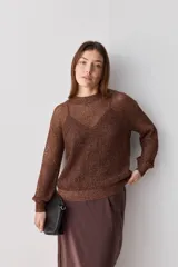 Sweater calado de punto negro, con cuello redondo y mangas largas, de diseño liviano ideal para superposiciones.