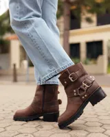 Botas cortas de cuero color caoba, con suela track negra, cierre lateral y correas con hebillas metálicas decorativas.