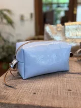 Neceser de cuero con acabado brillante, cierre superior y tirador de cuero en color natural.