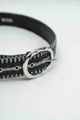 Cinturón de diseño trenzado en color negro con hilos plateados entrelazados, presenta una hebilla metálica ovalada de acabado brillante.