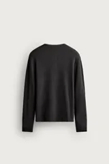 Camiseta relaxed fit de punto negro tejido en hilatura de algodón, con cuello redondo, cierre frontal de botonadura y manga larga con acabado en rib.