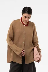 Camisa de lino color beige, de calce relajado, cuello redondo y cierre frontal de botones.