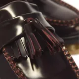 Mocasines Dr. Martens modelo Adrian en cuero color bordó, con doble borla, flecos decorativos y suela gruesa con costura visible.