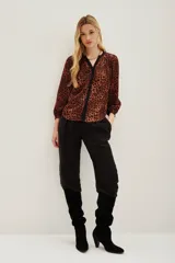 Camisa de manga larga con estampado animal print en tonos caramelo y negro. Presenta un escote en V con una solapa central en color negro y puños elásticos.