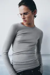 Jersey de punto fino color naranja, con cuello redondo y manga larga.