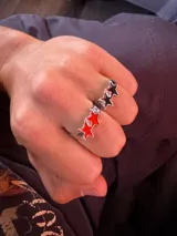 Set de dos anillos de metal plateado con diseño de estrellas esmaltadas en colores rojo y negro.