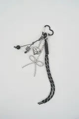 Llavero con mosquetón en forma de corazón negro, tiras de cordón estampado en blanco y negro, dije de corazón plateado, moño de cuentas y perlas.