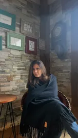 Bufanda de gran tamaño en color azul oscuro, confeccionada en lana merino con tejido doble y terminación de flecos en los extremos. Incluye una etiqueta de cuero con logo en una de las esquinas.