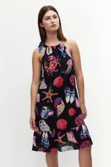 Vestido corto con escote halter y estampado de motivos marinos multicolores sobre fondo azul marino.