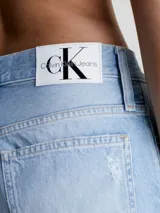 Jeans de mujer estilo mom, tiro alto, color celeste claro con efecto lavado y roturas grandes en ambas rodillas. El largo es tobillero.