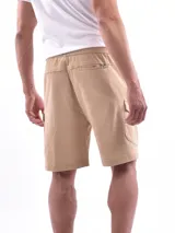 Bermuda cargo color beige, con cintura elástica y cordón ajustable. Presenta bolsillos laterales y bolsillos cargo con solapa en los costados.