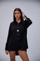 Camisa negra de manga larga, con cuello clásico y cierre frontal de botones blancos.