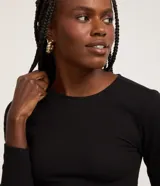 Blusa cropped negra de malla texturizada, con cuello redondo y mangas largas.