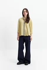 Camisa oversize color crema con detalles de puntilla roja en el frente.