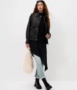 Campera de estilo urbano con corte oversized, confeccionada en poliuretano con base de poliéster. Presenta cuello clásico, cierre frontal con botones a presión, mangas largas y dos bolsillos frontales con tapa. El bajo cuenta con elástico para un mejor ajuste.