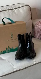 Bota corta estilo texana de charol negro, con punta fina y taco cuadrado bajo.