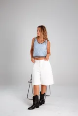 Blusa sin mangas tejida en crochet, color celeste con detalles de bordes en color marrón oscuro. Presenta un diseño de motivos florales geométricos y escote en V.