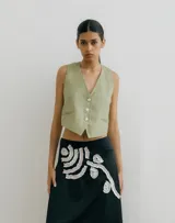 Chaleco corto color verde claro, confeccionado en lino, con cuello en V y cierre frontal con tres botones.