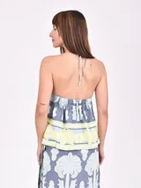 Top halter de color gris claro melange con estampado de palmeras y flores en tonos blanco y amarillo pálido.