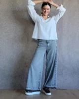 Pantalón de jean azul de tiro medio, con corte wide leg y ruedo deshilachado.