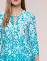Blusa azul y blanca con estampado floral y geométrico, de calce suelto, con escote redondo, abertura tipo keyhole en el pecho, mangas tres cuartos y ruedo amplio con silueta evasé.