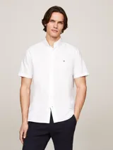 Camisa blanca de algodón Oxford, de corte regular, con cuello abotonado, manga corta y logo de Tommy Hilfiger bordado en el pecho.