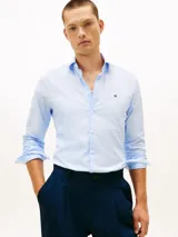 Camisa celestes de manga larga de Tommy Hilfiger, confeccionada en popelina de algodón con elastano. Presenta corte slim, cuello camisero clásico, cierre frontal con botones y el logo bordado en el pecho.