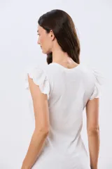 Remera de algodón color beige, de manga corta con volados de broderie, escote redondo y cuerpo liso.