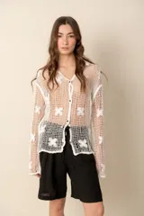 Camisa blanca de crochet con mangas largas y botones frontales.