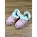 Pantuflas botitas color tostado con diseño acolchado y plataforma, forradas con corderito sintético blanco en el interior y el cuello. Cuentan con una pequeña etiqueta decorativa en el lateral.