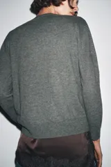 Jersey de punto liso color verde, con cuello redondo y manga larga. Confeccionado en lana suave.