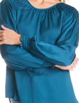 Blusa de satén color verde azulado con acabado sedoso y fluido. Escote a la base con frunce perimetral, mangas largas estilo balloon con detalle de punto smock en hombros y puños. Espalda con abertura tipo gota y botón forrado a tono.