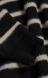 Sweater de cuello redondo con diseño de rayas horizontales en blanco y negro. Confeccionado en tejido de punto con textura suave, corte oversize y terminaciones en punto rib en cuello, puños y ruedo.