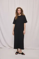 Vestido largo negro de algodón, de corte relajado, silueta recta, cuello redondo, mangas cortas amplias y tajos laterales.