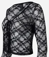 Blusa de manga larga confeccionada en encaje floral transparente, con escote en V y cierre frontal mediante lazos.